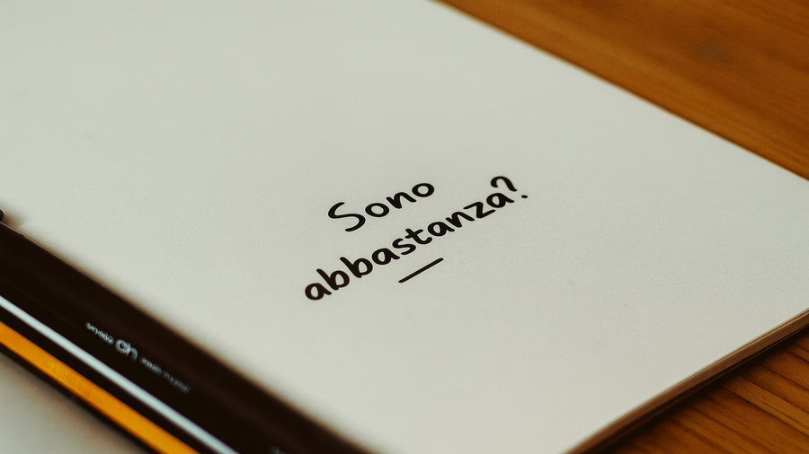 Quaderno aperto con la frase ‘Sono abbastanza?’ scritta a mano, simbolo del sentirsi non abbastanza e della ferita da inadeguatezza